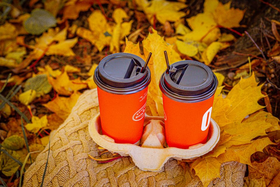 Koffiekop met kaneelstokjes in herfstige setting.